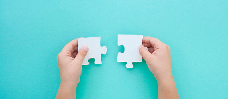 A person holding two puzzle pieces that fit together.