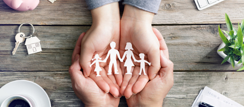 Two sets of hands holding one another with a silhouette of a family symbol in their hands.